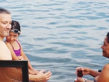 Family sitting by swimming pool