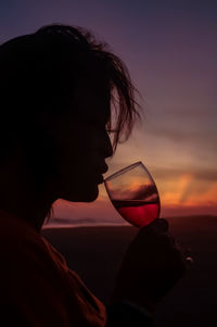 Close-up of woman drinking against sky during sunset