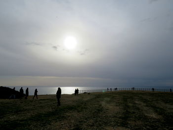 Silhouette people at beach against sky during sunset