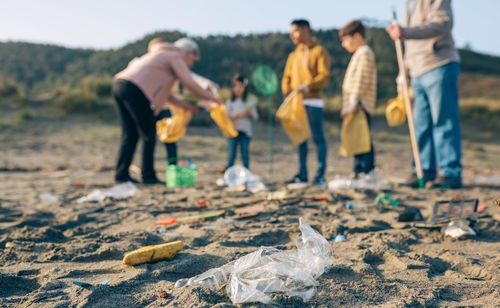 Grandparents and grandchildren cleaning while standing at beach