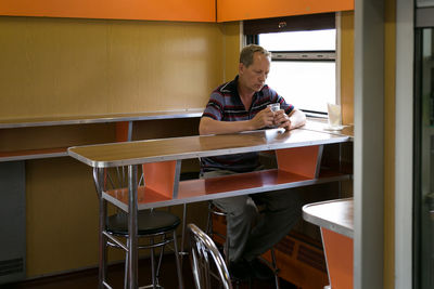 Young man using laptop while sitting on table