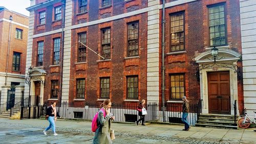 People walking on street against buildings in city