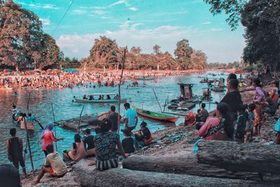 Group of people by boats moored in water