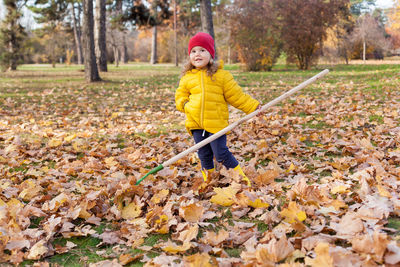Portrait girl raking leaves during autumn