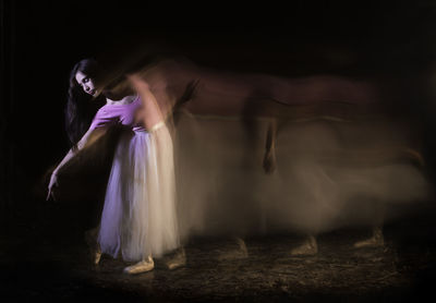 Young woman dancing against black background