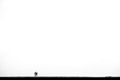 Rear view of silhouette man walking against clear sky