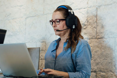 Woman working with her laptop and is focused on listening with her headphones