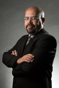 Portrait of mature bald businessman standing against gray wall