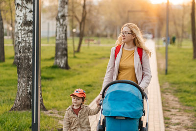 Mom walks with stroller and toddler son in the park