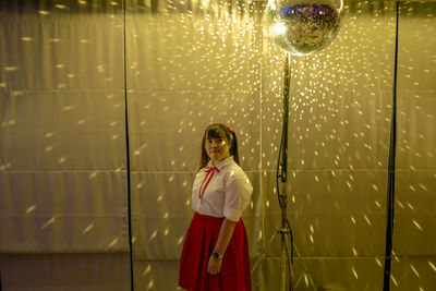 Portrait of woman standing by disco ball