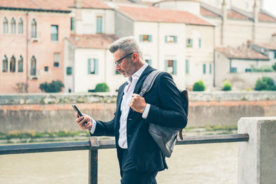 Businessman using mobile phone walking in city street and commut to work texting on smartphone.