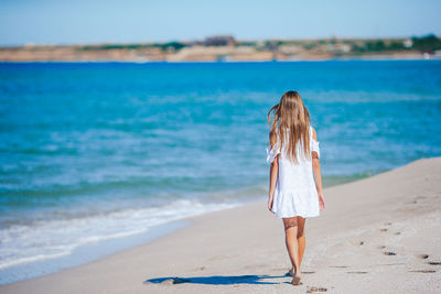 Rear view of woman standing at beach