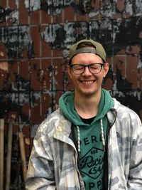 Portrait of smiling young man standing against graffiti