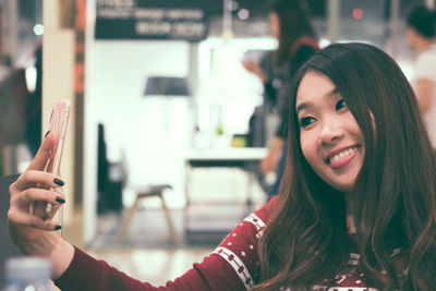 Close-up of smiling young woman using mobile phone