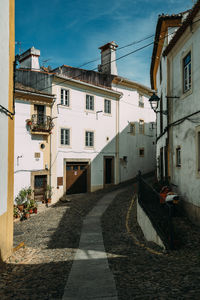 Footpath amidst buildings against sky