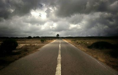 Empty road against cloudy sky