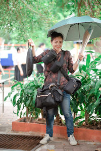 Full length portrait of smiling woman standing in rain