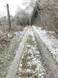 Dirt road along snow covered land