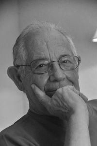 Close-up portrait of senior man wearing eyeglasses sitting at home