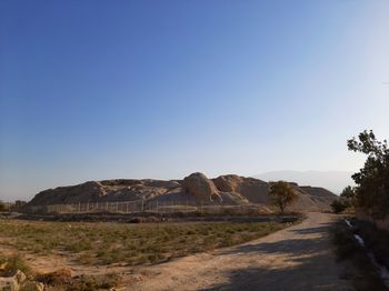 Scenic view of arid landscape against clear blue sky