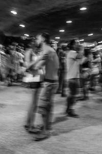 Blurred motion of people walking on illuminated street at night