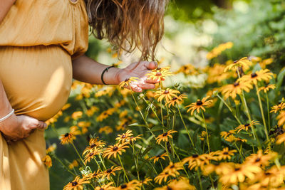 Woman and flowering plants on field