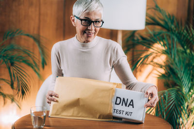 Midsection of woman holding eyeglasses while sitting on table