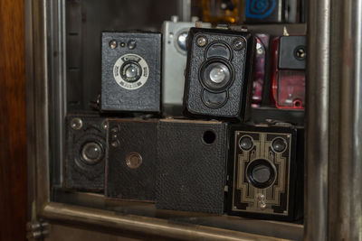 Old vintage box cameras stored in a wooden shelf.