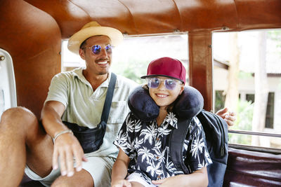 Happy father sitting with smiling daughter wearing neck pillow in van