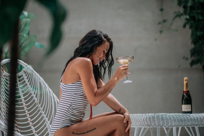 Rear view of woman drinking glass sitting outdoors