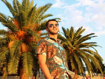 Low angle view of young man looking away against trees