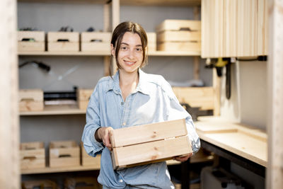 Portrait of smiling young woman standing against wall