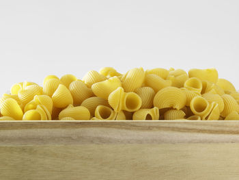 Close-up of raw pasta in crate against white background