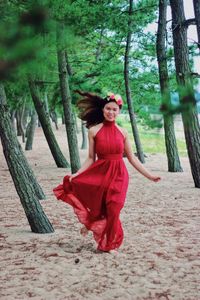 Woman standing by tree trunk in forest