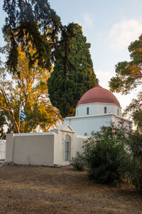 Trees by building against sky