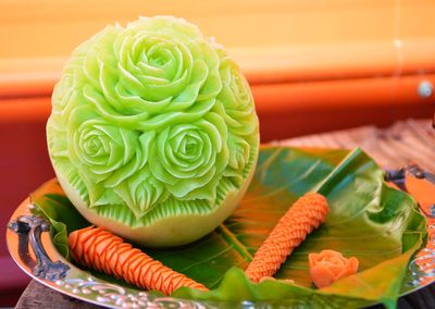 Decorative carved honeydew melon and carrot on plate