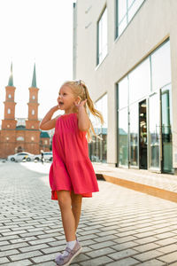 Full length of young woman standing against building