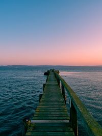 Pier over sea against sky during sunset