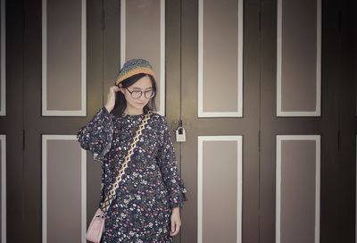 Young woman standing against closed door