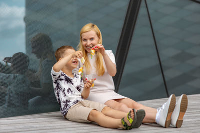 Happy blond woman and little boy sitting on terrace and eating sweets. mother and son 