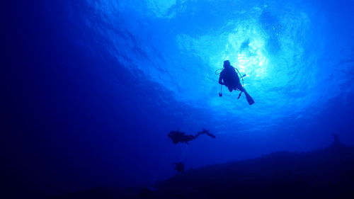 Low angle view of silhouette man swimming in sea