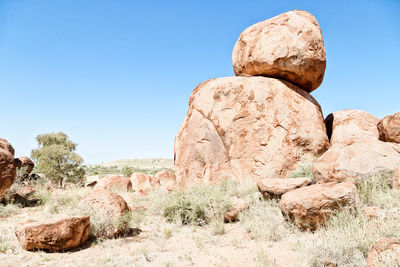 Rock formations on landscape against clear blue sky