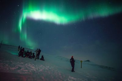 People on snowy mountain against idyllic aurora