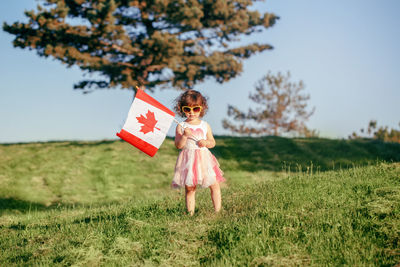Girl holding canadian flag standing on land
