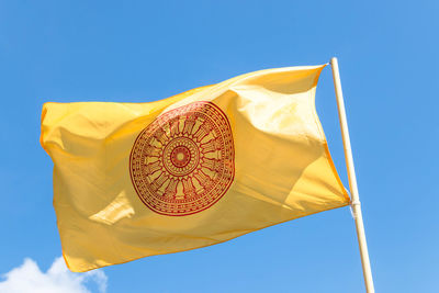 Low angle view of yellow flag against clear blue sky