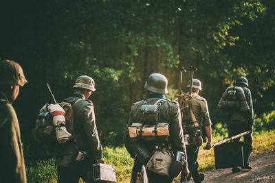 Men in uniforms walking against trees in forest