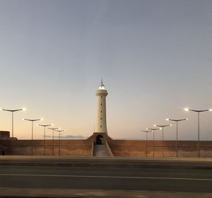 Street light by illuminated building against sky