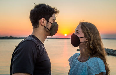 Portrait of friends against sea during sunset