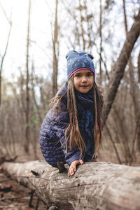 Portrait of girl wearing sunglasses on tree trunk