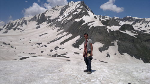 Full length of woman standing on snowcapped mountain against sky